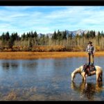 david cowley standing on horse back while in lake