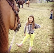 young girl looking at horse and smiling